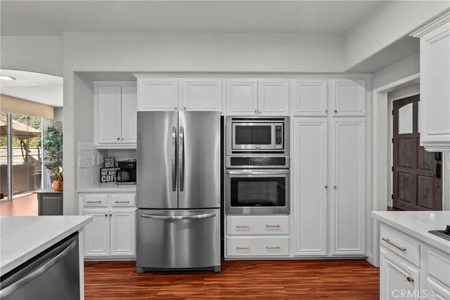 a kitchen with cabinets stainless steel appliances and wooden floor