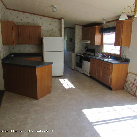 2000 Booth Road Hallstead, PA 18822 - Photo 8 of 15 a kitchen with granite countertop a refrigerator a sink a stove and wooden cabinets