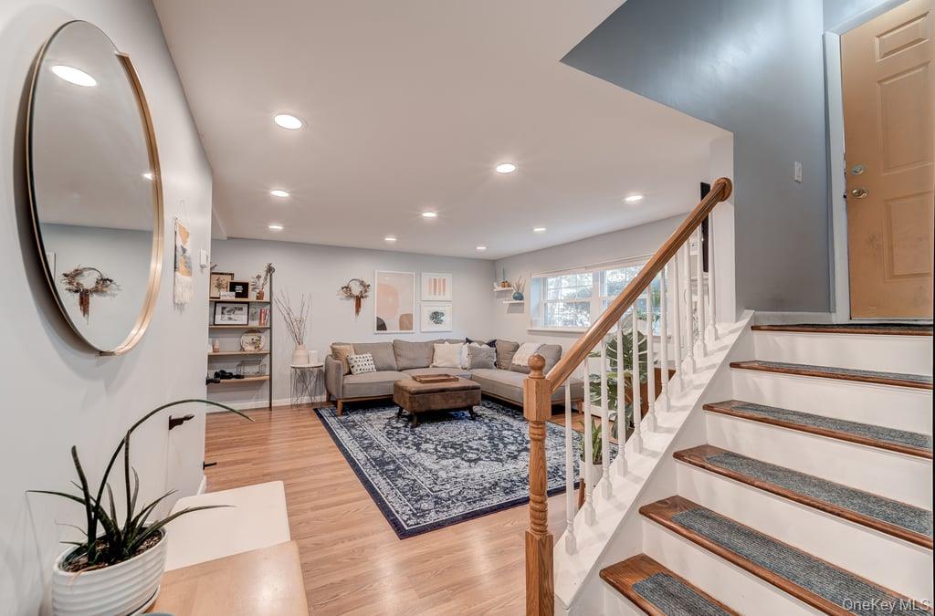 Living room featuring light wood-type flooring, recessed lighting, and stairway. Photo may not represent recent decor.
