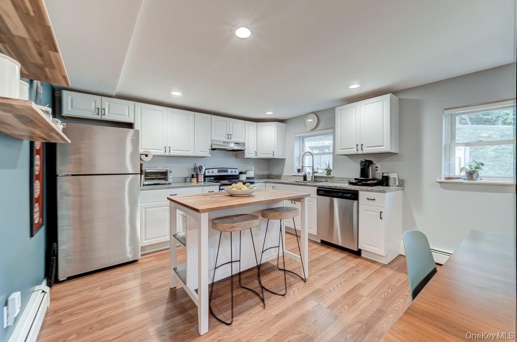 4 Forge Gate Drive, Unit F3 Cold Spring, NY 10516 - Photo 7 of 20 a kitchen with granite countertop a refrigerator a stove a sink dishwasher and white cabinets with wooden floor