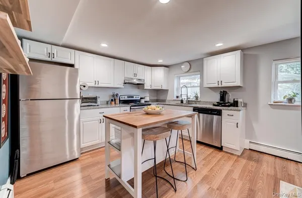 a kitchen with stainless steel appliances granite countertop a refrigerator a stove a sink dishwasher and a refrigerator with wooden floor