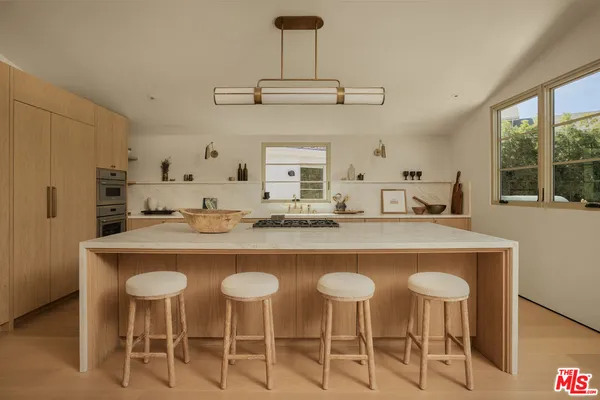 a kitchen with stainless steel appliances a dining table chairs and large window