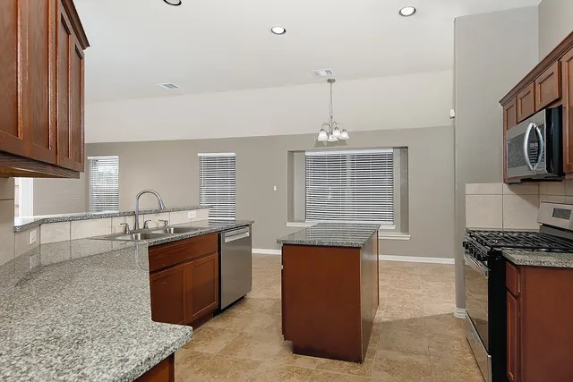 a kitchen with granite countertop a sink stove and refrigerator