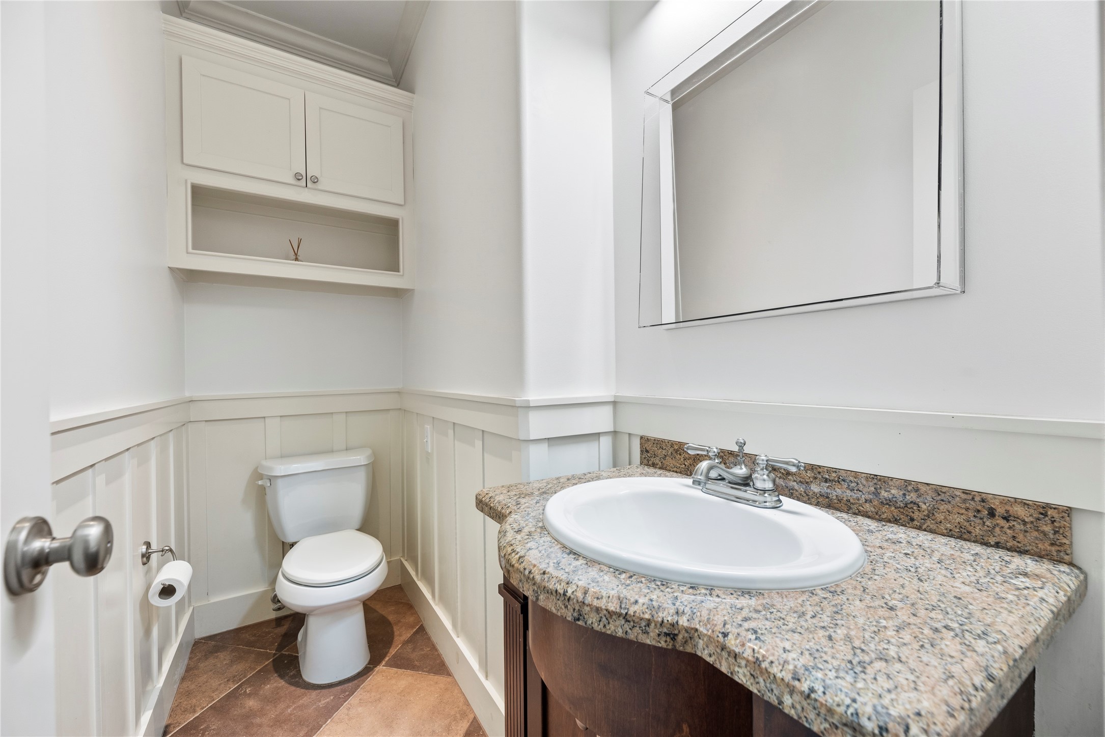 1505 Prince Street Houston, TX 77008 - Photo 16 of 39 The downstairs powder room impresses with wainscoting, a freestanding vanity with a built-in granite counter, and a storage cabinet — spacious and thoughtfully finished.