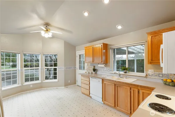 a large kitchen with kitchen island a large window cabinets a sink and stainless steel appliances