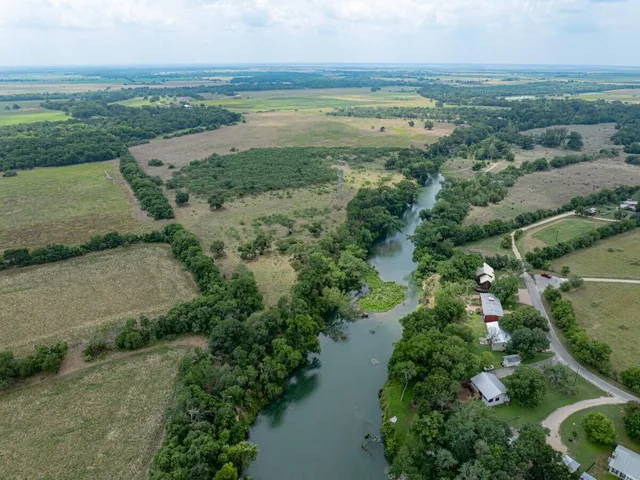 an aerial view of a houses with outdoor space and trees all around