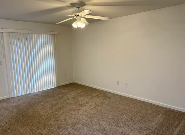 an empty room with a window and a fan