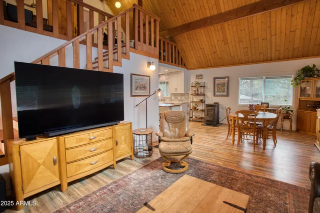 a living room with furniture a flat screen tv and kitchen view