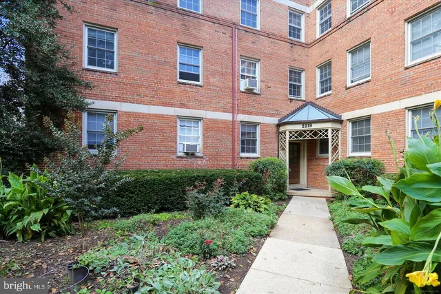 front view of a brick house with a yard and potted plants