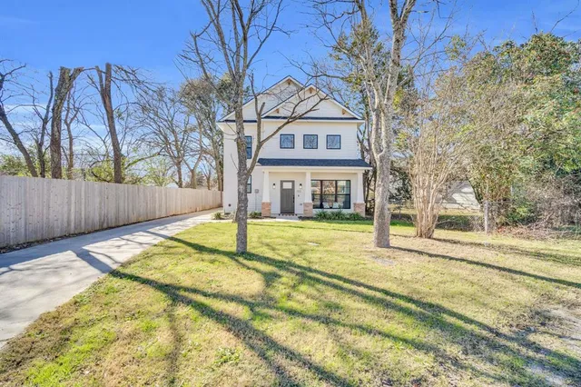 a view of a house with a large tree and wooden fence