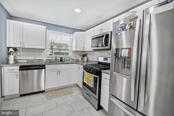 a kitchen with stainless steel appliances granite countertop a refrigerator sink and stove