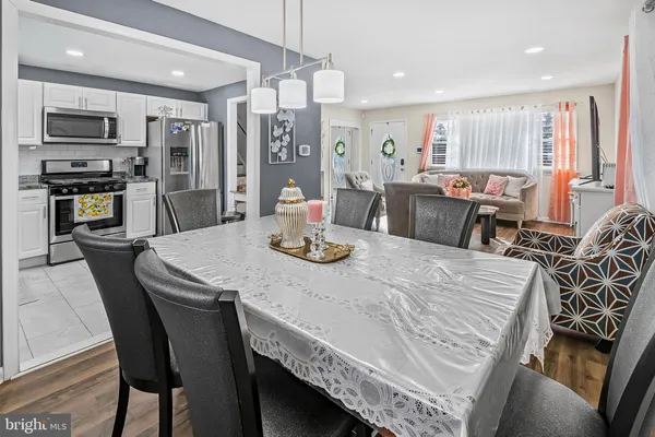 a kitchen with stainless steel appliances granite countertop a stove a refrigerator a kitchen island a table and chairs