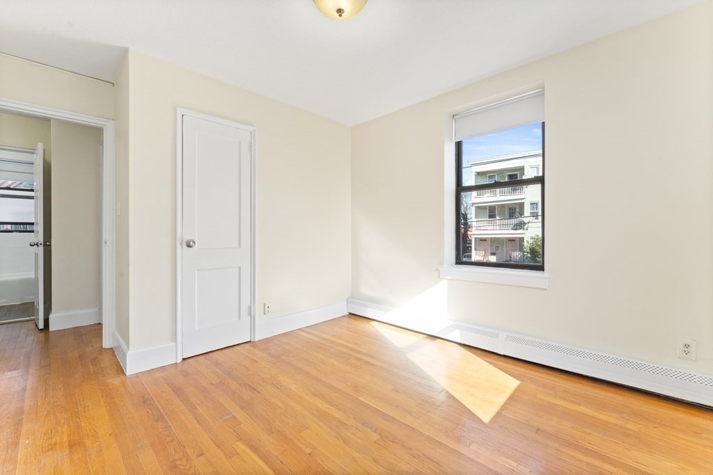 11 Victory Road, Unit 32 Boston, MA 02122 - Photo 4 of 16 wooden floor in an empty room with a window