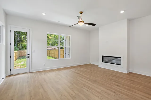 a view of an empty room with wooden floor and a window