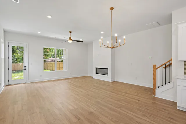 a kitchen with stainless steel appliances granite countertop a sink a stove a refrigerator and white cabinets with wooden floor