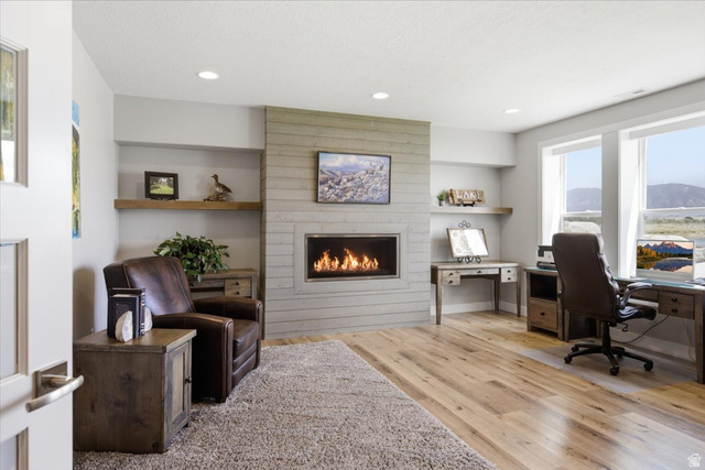 21 Pier Place Tooele, UT 84074 - Photo 66 of 112 Contemporary living space featuring a modern fireplace with a horizontally paneled surround, light wood-finish flooring, recessed lighting, expansive windows, and built-in shelving