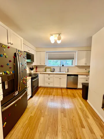 a large kitchen with cabinets wooden floor and stainless steel appliances