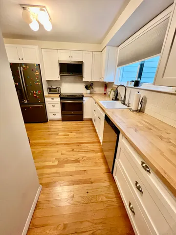 a large kitchen with stainless steel appliances wooden floor sink and wooden cabinets