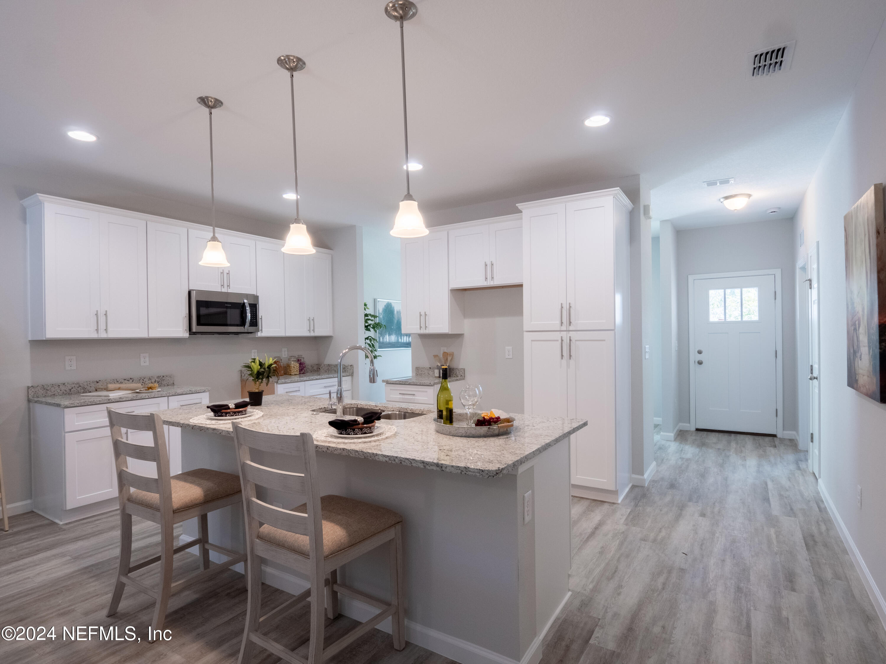 4011 Spring Glen Road Jacksonville, FL 32207 - Photo 12 of 38 a kitchen with stainless steel appliances kitchen island granite countertop a refrigerator a stove top oven a sink dishwasher and white cabinets with wooden floor