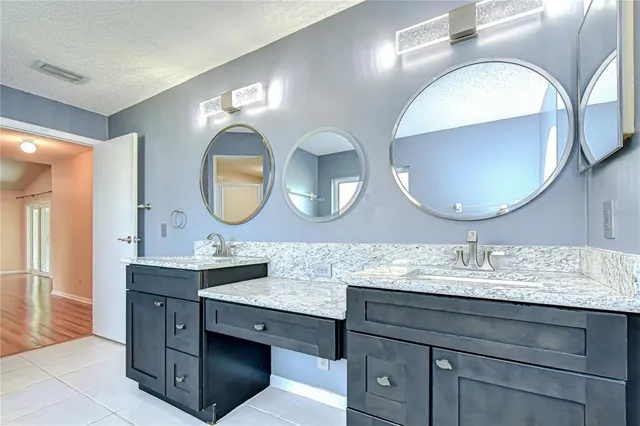 a en suite bathroom with a granite countertop tub sink and mirror
