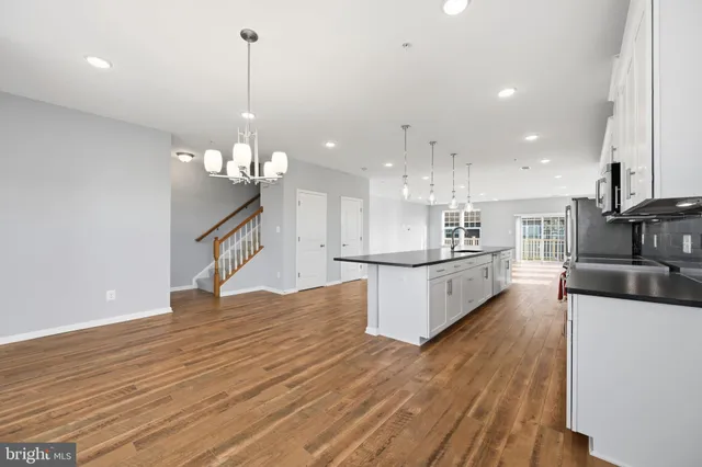 a view of kitchen with kitchen island stainless steel appliances sink and wooden floor