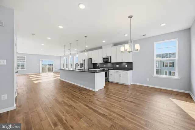 a view of kitchen with kitchen island white cabinets wooden floor and a sink