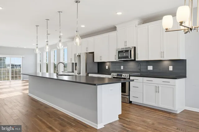 a large kitchen with stainless steel appliances granite countertop a stove a sink a microwave and wooden cabinets