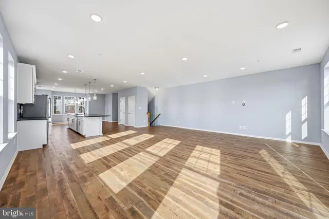 a large kitchen with kitchen island a stove a refrigerator a oven with white cabinets and wooden floor