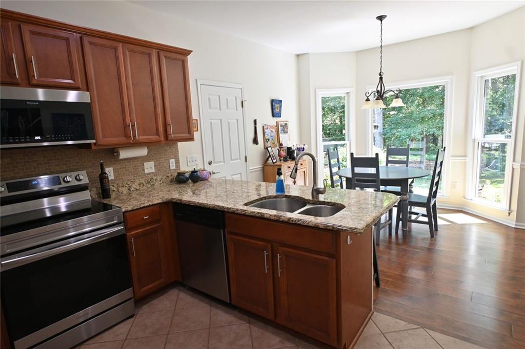 4865 Settles Point Road Suwanee, GA 30024 - Photo 9 of 25 a kitchen with stainless steel appliances granite countertop a stove a sink and a microwave