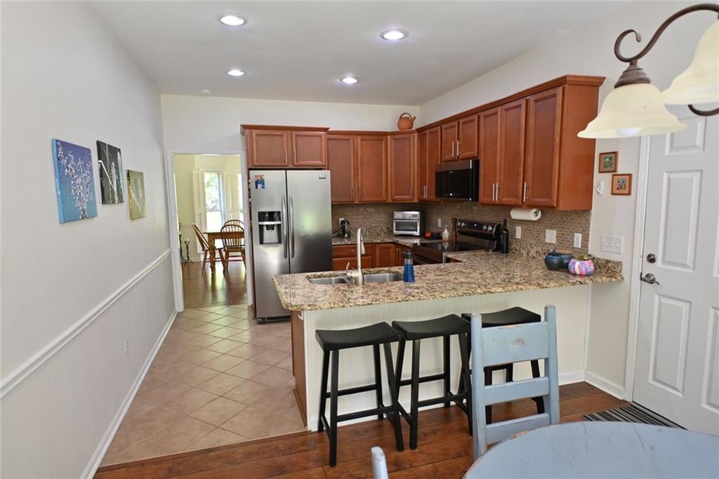 4865 Settles Point Road Suwanee, GA 30024 - Photo 10 of 25 a kitchen with stainless steel appliances granite countertop a stove a refrigerator a sink a dining table and chairs with wooden floor