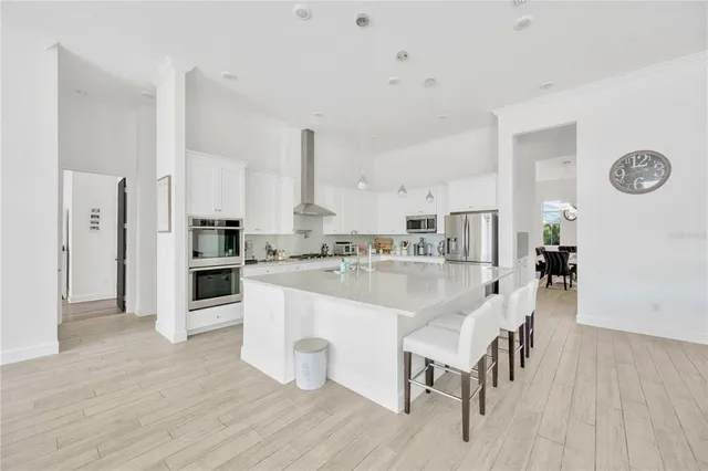 a large white kitchen with wooden floor and chairs