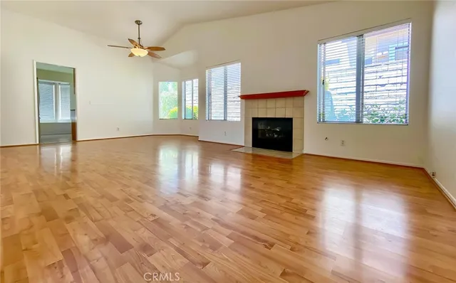 an empty room with wooden floor a fireplace and windows