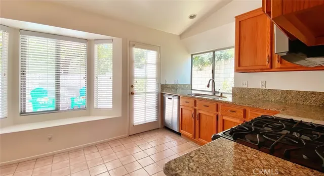 a kitchen with stainless steel appliances granite countertop a stove a sink and a large window