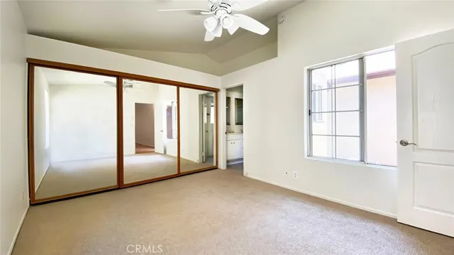 an empty room with chandelier fan and windows