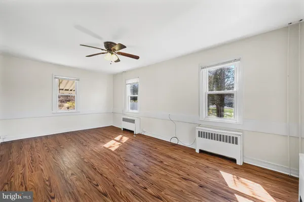 a view of an empty room with a window and wooden floor