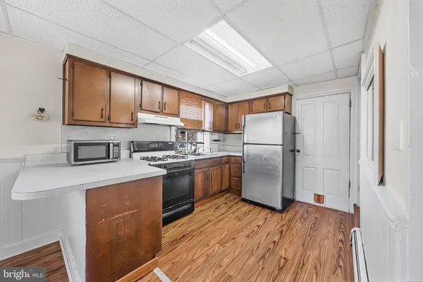 a kitchen with stainless steel appliances granite countertop a refrigerator a stove top oven a sink and dishwasher with wooden floor
