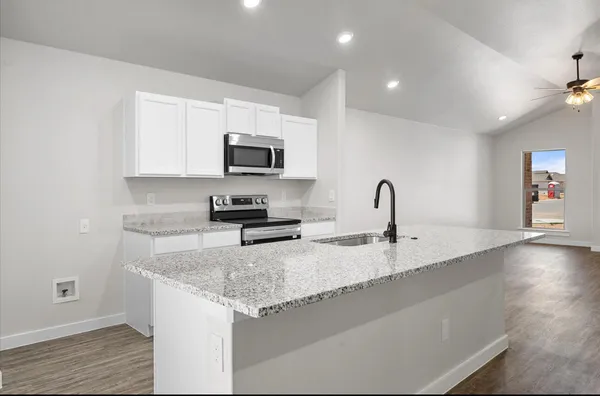 a kitchen with granite countertop a sink and a stove top oven