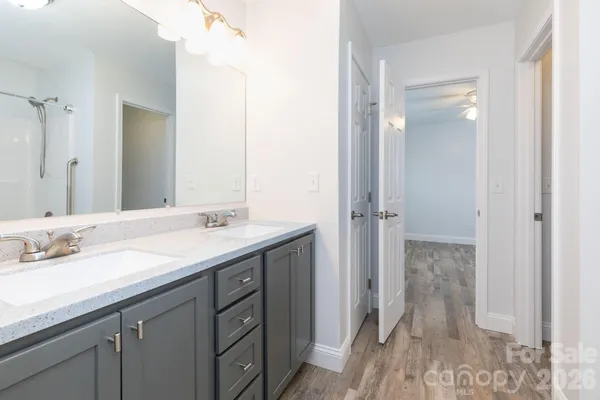 a bathroom with a granite countertop sink two mirror and a shower