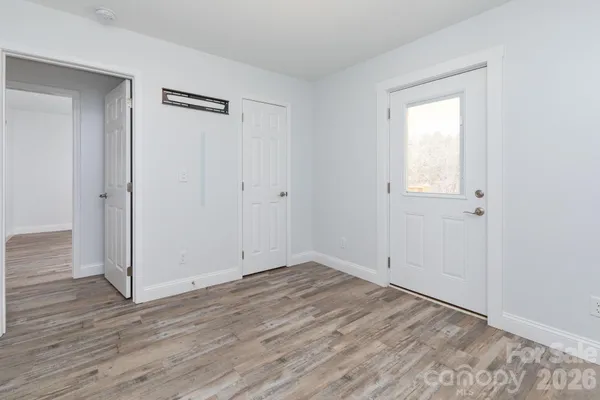 a view of an empty room with wooden floor and closet