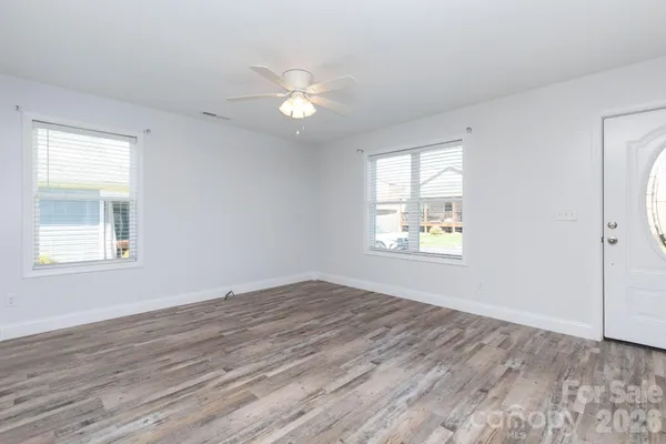 a view of an empty room with wooden floor and a window