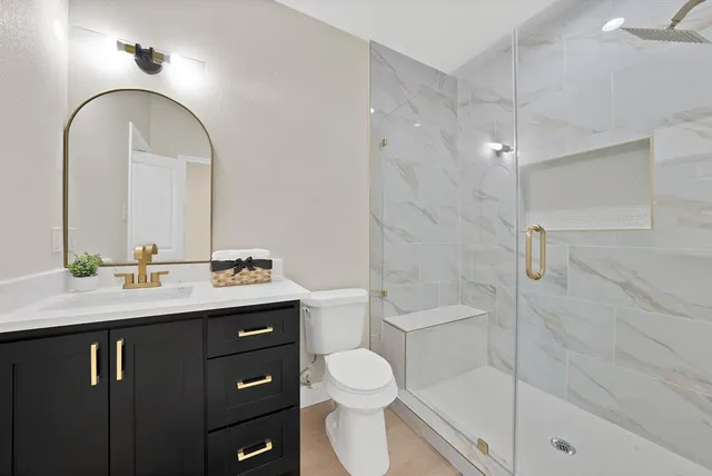 a bathroom with a sink a toilet and shower