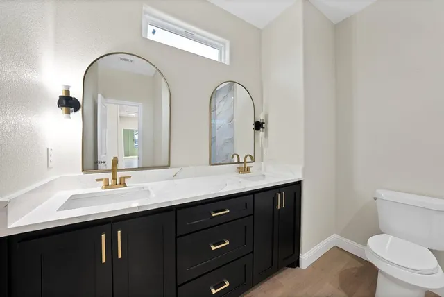 a bathroom with a granite countertop toilet a sink and a mirror