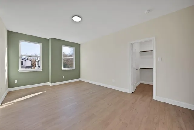 an empty room that has a window and wooden floor