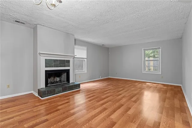 a view of empty room with wooden floor and fireplace