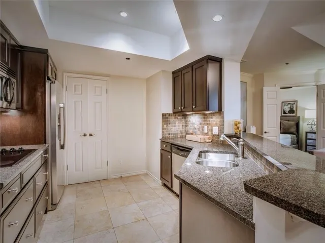 a kitchen with granite countertop a sink a stove and refrigerator