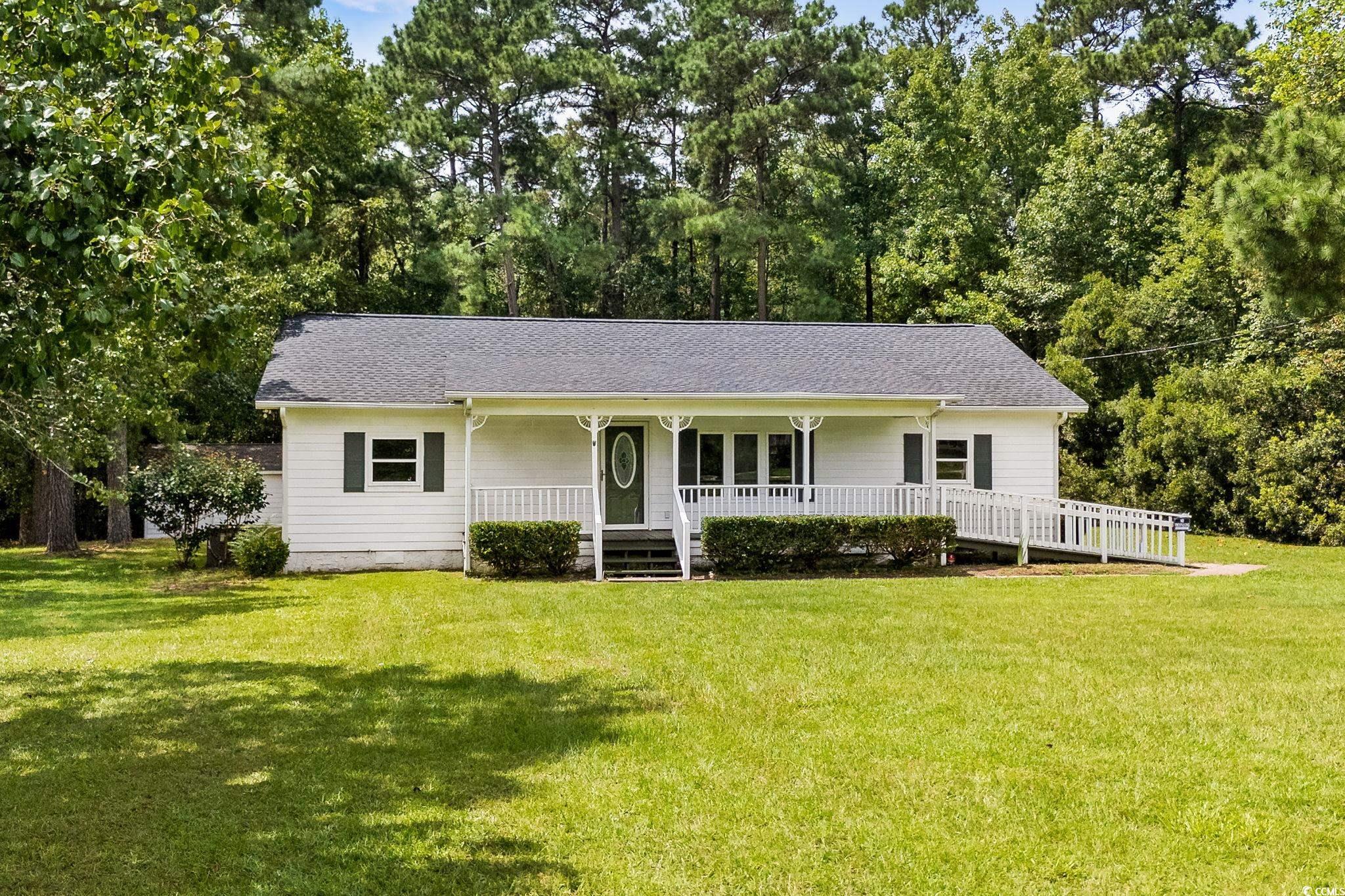 Single story home with covered porch, a front yard, and a shingled roof