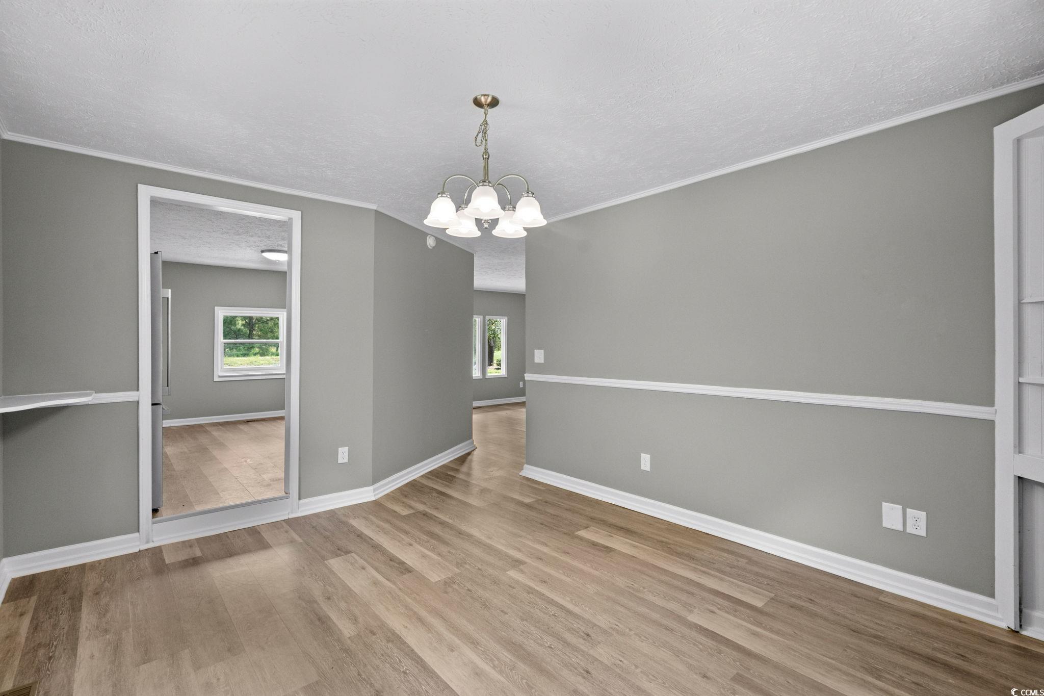 450 Highway 348 Loris, SC 29569 - Photo 11 of 37 Unfurnished dining area featuring crown molding, light wood finished floors, a chandelier, and a textured ceiling