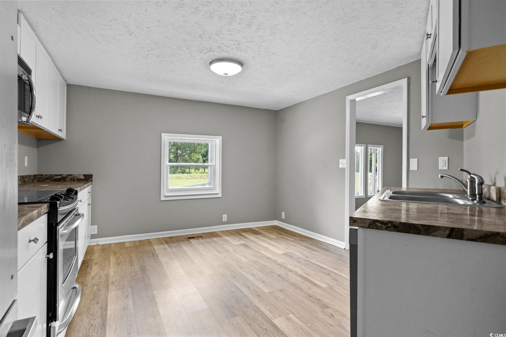 450 Highway 348 Loris, SC 29569 - Photo 12 of 37 Kitchen with dark countertops, appliances with stainless steel finishes, a textured ceiling, light wood finished floors, and white cabinets