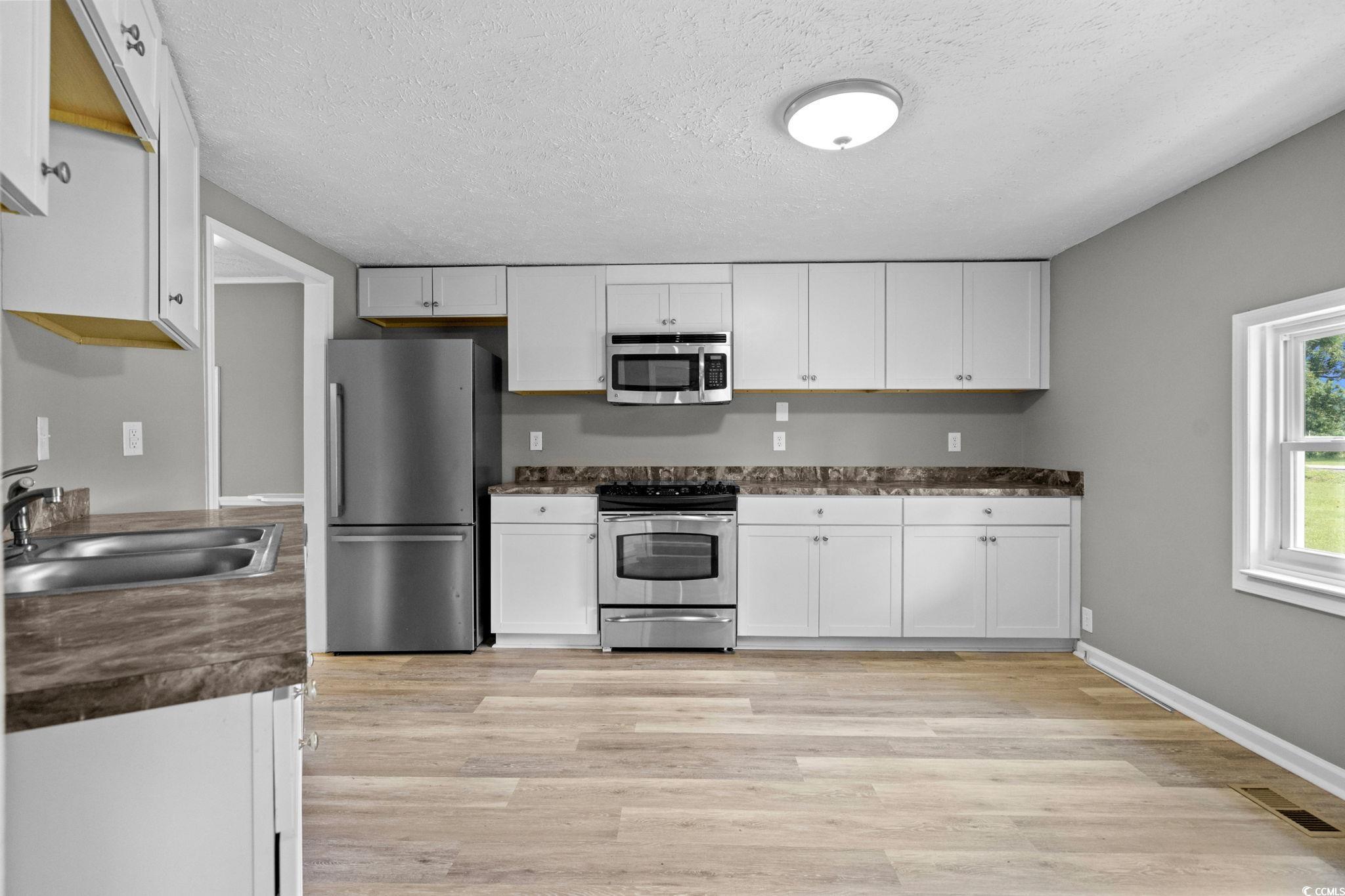 450 Highway 348 Loris, SC 29569 - Photo 13 of 37 Kitchen featuring dark countertops, stainless steel appliances, white cabinetry, and a textured ceiling