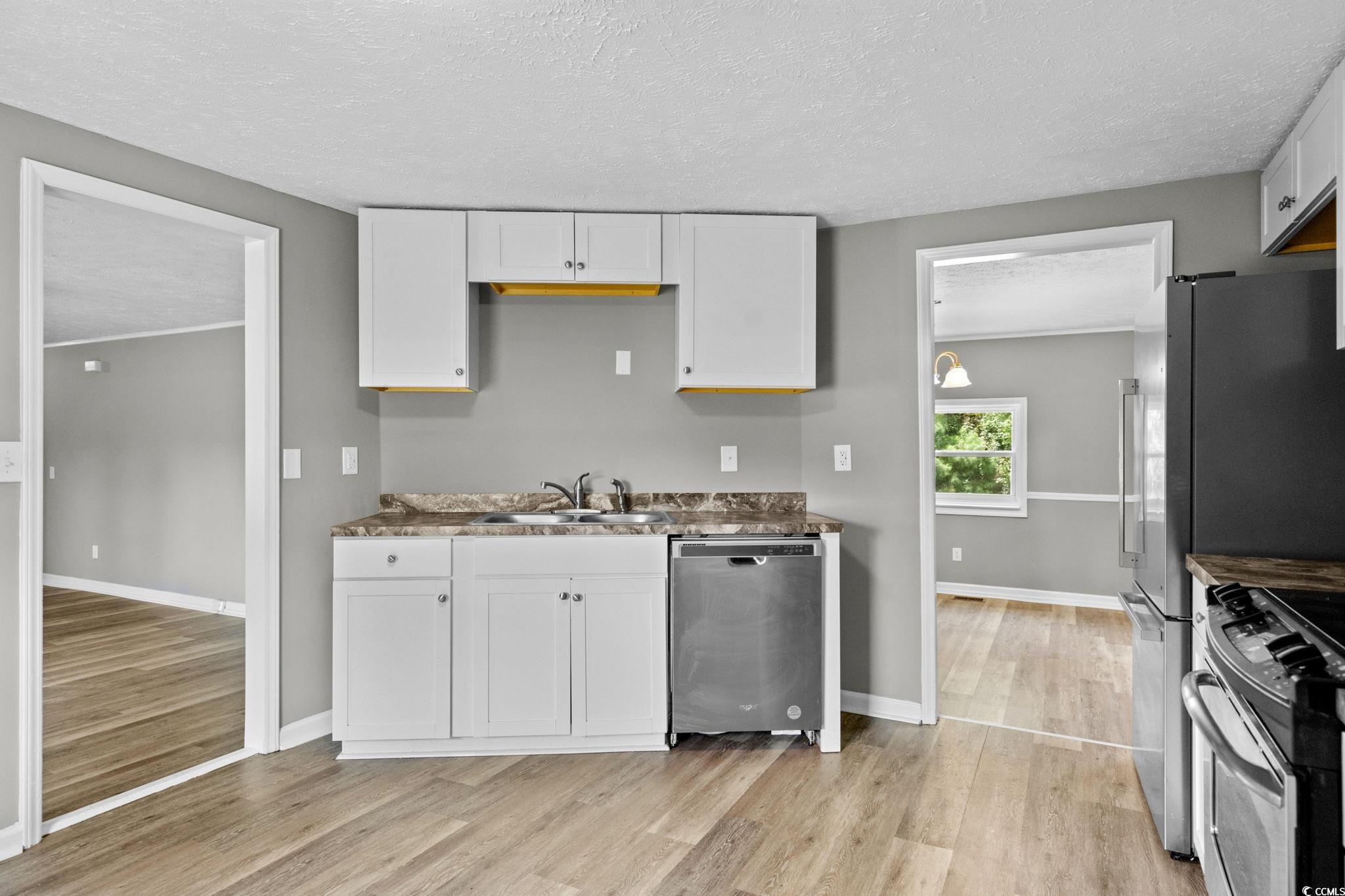 450 Highway 348 Loris, SC 29569 - Photo 16 of 37 Kitchen featuring a textured ceiling, light wood-style flooring, stainless steel appliances, and white cabinetry